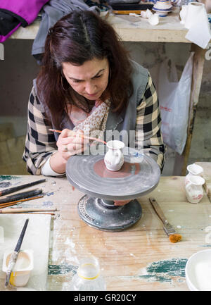 Peinture à la main la jante sur un pot en céramique. Une femme peint le modèle de jante sur un morceau de la poterie à la Céramique Banque D'Images