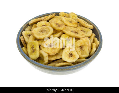 Chips de banane déshydratée dans un vieux bol en grès isolé sur un fond blanc. Banque D'Images