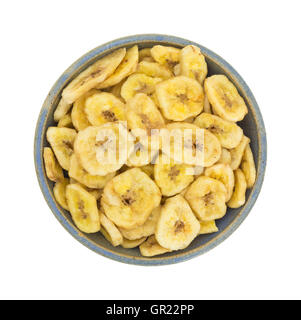 Vue de dessus de chips de banane déshydratée dans un vieux bol en grès isolé sur un fond blanc. Banque D'Images