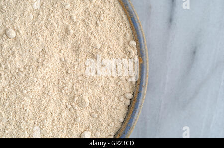 Haut de page Fermer la vue d'un bol rempli avec de la farine de quinoa sur une planche à découper en marbre gris. Banque D'Images