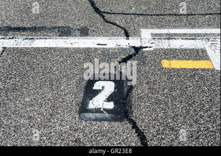 Signe de la position numéro deux sur speedway piste de départ avec la ligne jaune et endommagé l'asphalte ancien Banque D'Images