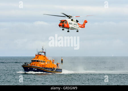 Winchman du Sikorsky S-92 de la Garde côtière irlandaise est ramené vers le bas pour l'embarcation de Portrush, RNLB William Gordon Burr Banque D'Images