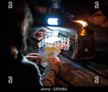 Les enfants jouent le jeu de carte Uno par une bougie d'huile tout en camping à French Creek State Park California Banque D'Images