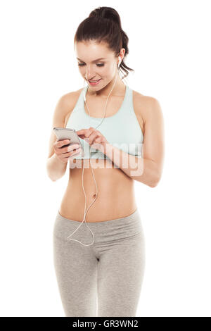 Fitness petite fille avec un smartphone sur un fond blanc, bénéficie d'un entraînement sportif, séance de gym Banque D'Images