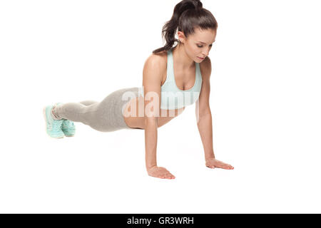 Athletic woman doing push-ups sur un fond blanc. Modèle de remise en forme avec une belle et athlétique du Banque D'Images