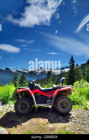 Rouge et Noir ATV (véhicule tout terrain) stationné sur la forêt montagneuse de gravier près de Whistler BC ensoleillée. Nature HDR Photo verticale Banque D'Images