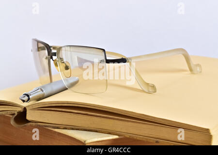 Libre de plusieurs livres anciens verres et stylo sur fond lumineux Banque D'Images