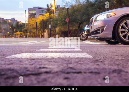 Voiture et moto en attente avec voyant rouge sur une rue de la ville au coucher du soleil. Low angle view Banque D'Images