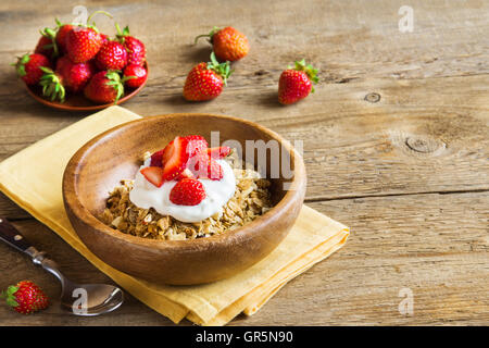Granola fait maison avec du yogourt et fraises dans bol sur fond de bois with copy space Banque D'Images