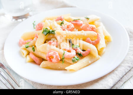 Pâtes penne aux crevettes, sauce crème et parmesan râpé sur fond blanc Banque D'Images