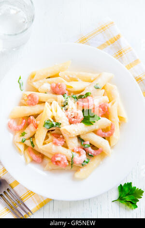 Pâtes penne aux crevettes, sauce crème et parmesan râpé sur fond blanc Banque D'Images