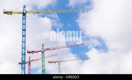 Quatre grues peintes en différentes couleurs avec ciel nuageux dans l'arrière-plan Banque D'Images