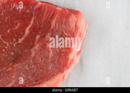 Haut de page Fermer la vue d'un raccourci naturel sur un pavé de rumsteak en planche à découper. Banque D'Images