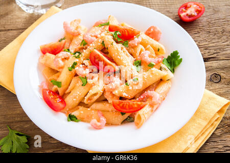 Pâtes penne aux crevettes, sauce tomate, le persil et le parmesan râpé sur fond de bois rustique Banque D'Images