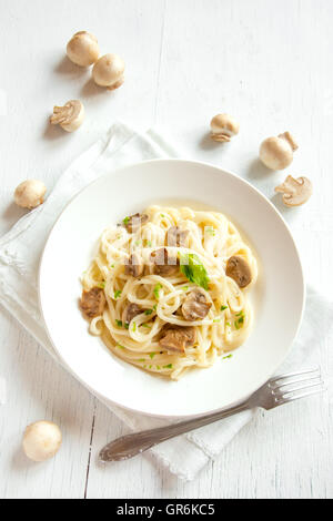 Les pâtes Spaghetti aux champignons grillés et verts sur fond de bois blanc Banque D'Images