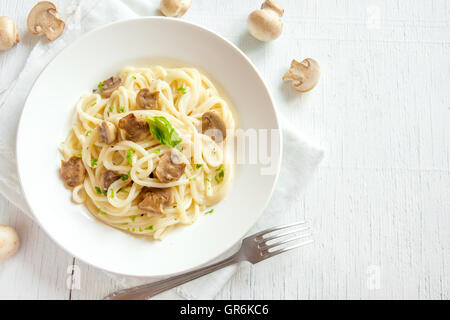 Les pâtes Spaghetti aux champignons grillés et verts sur fond de bois blanc with copy space Banque D'Images