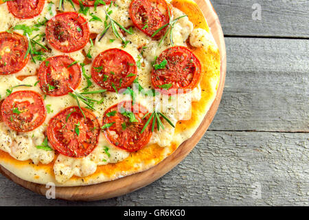 Pizza Margherita avec les tomates, le fromage, le basilic et le romarin sur fond de bois rustique with copy space Banque D'Images