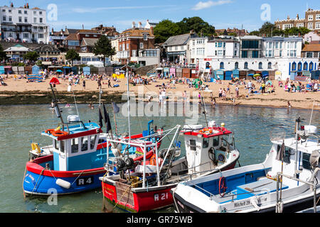 Broadstairs resort ville, vue du port de bateaux de pêche puis la principale plage bondés de gens sur chaude journée d'été avec la ville en arrière-plan. Banque D'Images