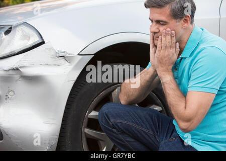 L'inspection des dommages après le pilote malheureux accident de voiture Banque D'Images