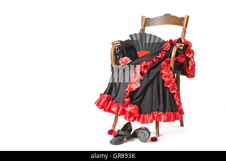 Les vêtements et chaussures pour la danse flamenco sont couchés sur une chaise en bois vintage. Tout est sur le fond blanc. Banque D'Images