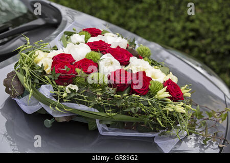 Heart-Shaped Voiture mariée Bouquet roses blanches et rouges sur voiture gris Banque D'Images