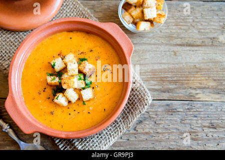 Soupe de tomates et carottes légumes avec croûtons et le persil en pot en céramique sur fond de bois rustique with copy space Banque D'Images