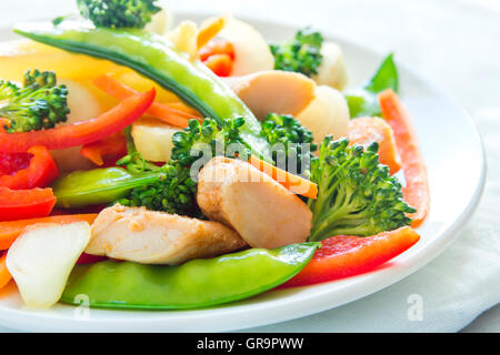 Des légumes sautées avec du poulet sur plaque blanche close up Banque D'Images