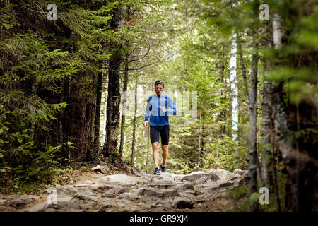 Jeune homme sportif lignes actives dans le sentier des roches dans les bois en montagne marathon Banque D'Images