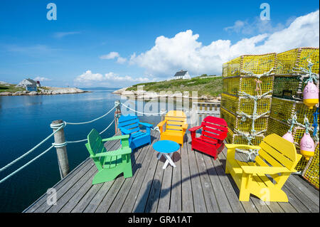 Des chaises Adirondack s'asseoir à côté de piles de casiers à homard sur un pont d'un village de pêcheurs de Peggy's Cove en Nouvelle-Écosse Banque D'Images