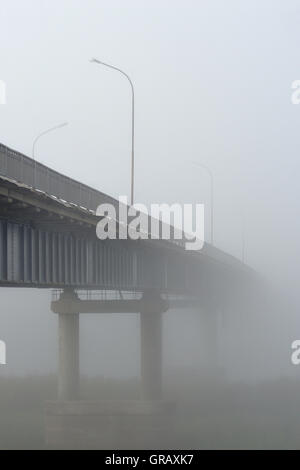 Tôt le matin et en début d'automne. Le pont disparaît dans un épais brouillard. Banque D'Images