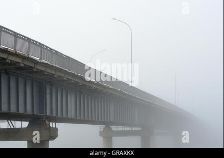 Tôt le matin et en début d'automne. Le pont disparaît dans un épais brouillard. Banque D'Images