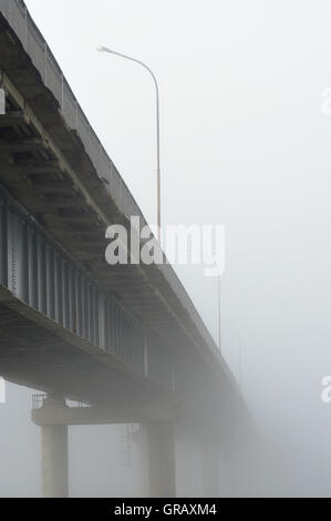 Tôt le matin et en début d'automne. Le pont disparaît dans un épais brouillard. Banque D'Images