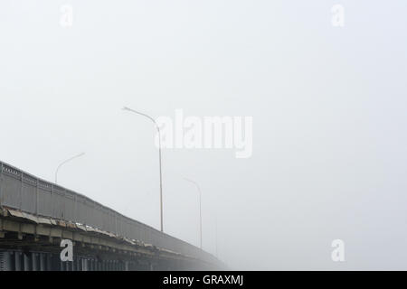 Tôt le matin et en début d'automne. Le pont disparaît dans un épais brouillard. Banque D'Images