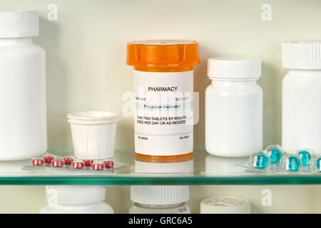 Bouteille d'ordonnance sur l'armoire à pharmacie étagère en verre avec des médicaments. Les étiquettes sont fictifs et créé par le photographe. Banque D'Images