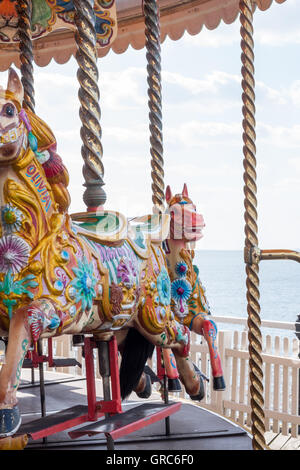 Chevaux en bois peint de couleur sur un rond-point du carrousel (merry-go-round) par le front de mer de Brighton, East Sussex, UK Banque D'Images