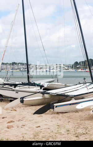 Une rangée de bateaux et catamarans beachable sur le sable à la Trinité-sur-Mer, Bretagne, France, avec la marina à l'arrière-plan Banque D'Images