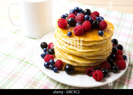 Petit-déjeuner de crêpes au miel et de baies fraîches sur la plaque blanche et tasse de café. Crêpes maison servi avec blueberry, ras Banque D'Images