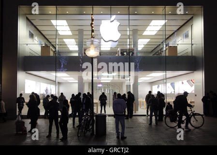 Groupe de personnes à l'aide de Hot Spot à un Apple Store fermé la nuit à Munich Banque D'Images