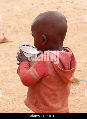 Petit garçon buvant dans une tasse, Himbas, en Namibie Banque D'Images