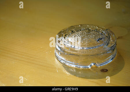 L'envers, vide de verre humide Cendrier sur table en bois Banque D'Images