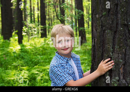 Enfant (garçon, serrant les mains) pin (arbre), le jeu et le plaisir piscine en été (parc). Concept de protection de l'environnement Banque D'Images