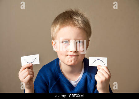 Jeune garçon sélectionnez entre les expressions positives et négatives Banque D'Images