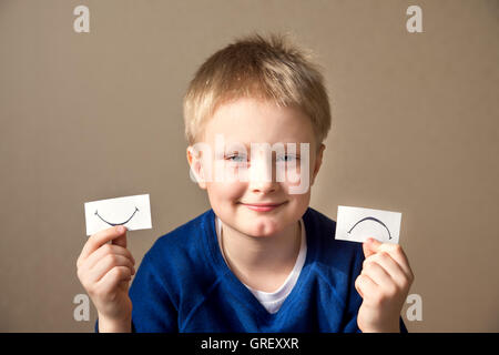 Jeune garçon sélectionnez entre les expressions positives et négatives Banque D'Images