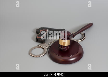 Judge's gavel, pistolet et menottes isolé sur fond gris Banque D'Images