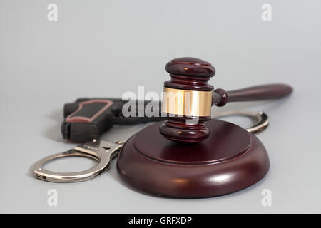 Judge's gavel, pistolet et menottes isolé sur fond gris Banque D'Images