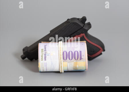 Mille francs suisses dans un rouleau, pistolet et fond gris Banque D'Images