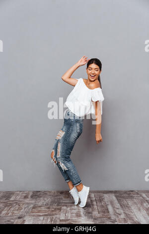 Belle cheerful smiling brunette girl debout sur ses pieds isolés sur un fond gris Banque D'Images