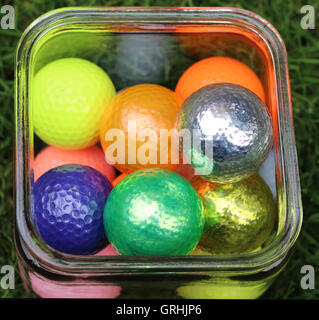 Contenant en verre avec des balles de golf de couleur, violet, vert, jaune, argent, or, orange, rose Banque D'Images