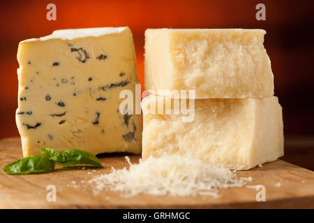 Morceaux de fromage bleu et le parmesan sur une planche à découper en bois d'être coupé avec un couteau à fromage avec des épices sur un restaurant en bois Banque D'Images