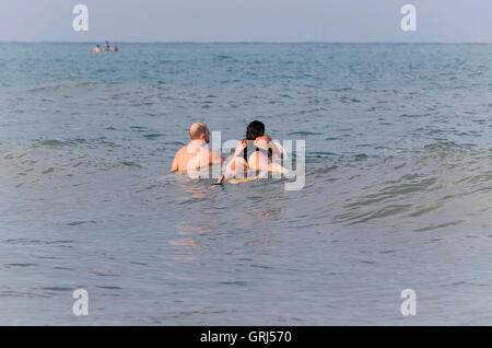 Couple de surfers tente de prendre des vagues avec leurs planches, dans la plage de Castellon de la Plana (Espagne). Fond coucher de soleil. Banque D'Images